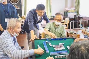 利用者が麻雀をしているところを見守る市長の写真