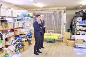 多様な布地などの材料の前で話す市長と代表取締役
