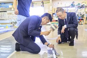 テントのハトメ打ち付け体験をする市長